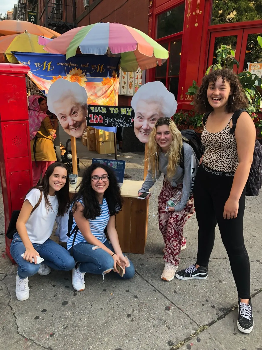 Students smiling at the Grandma Stand on a city street