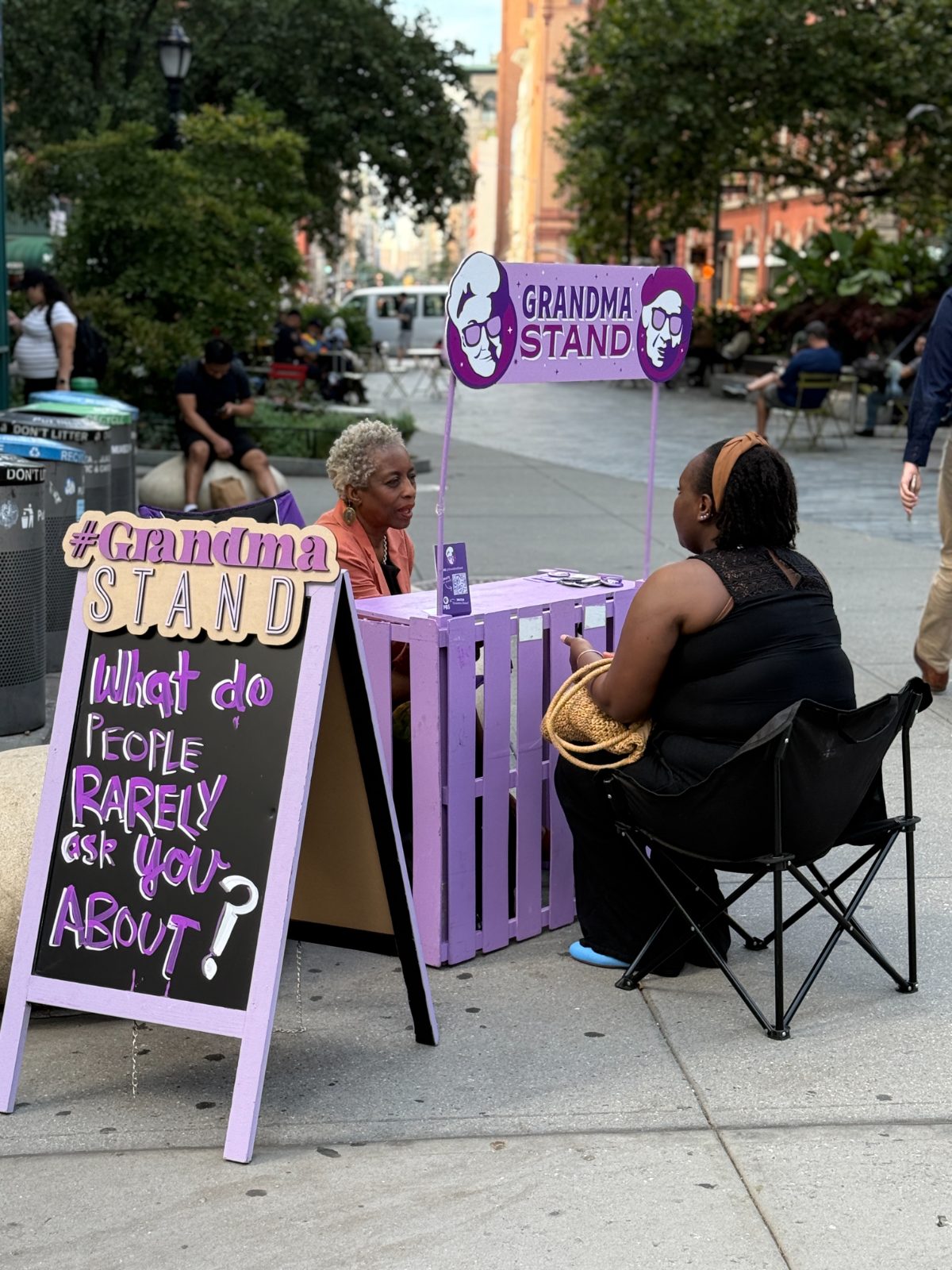 A grandma and a visitor talking across the stand downtown